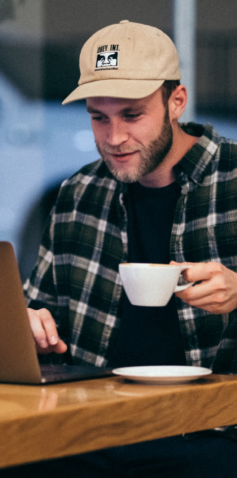 Man holding a cup while using laptop